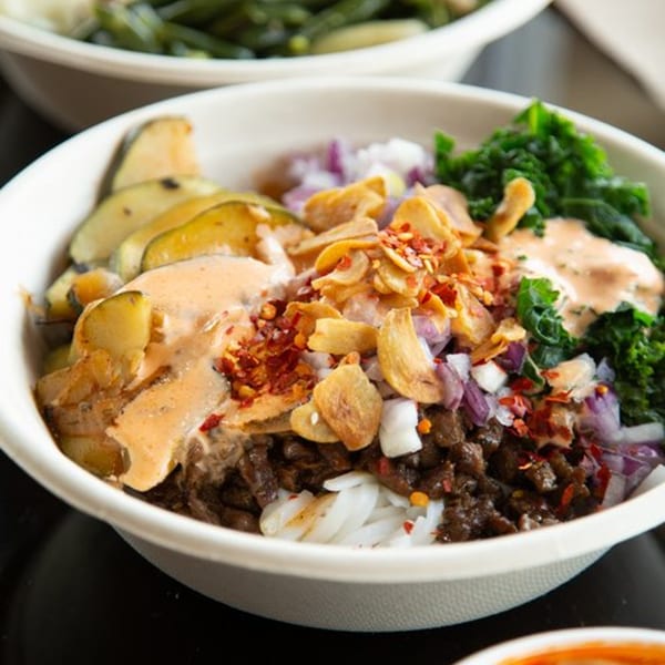 Oryza Asian Grill bowl with meat, rice noodles, vegetables, sauce, and crispy garlic.